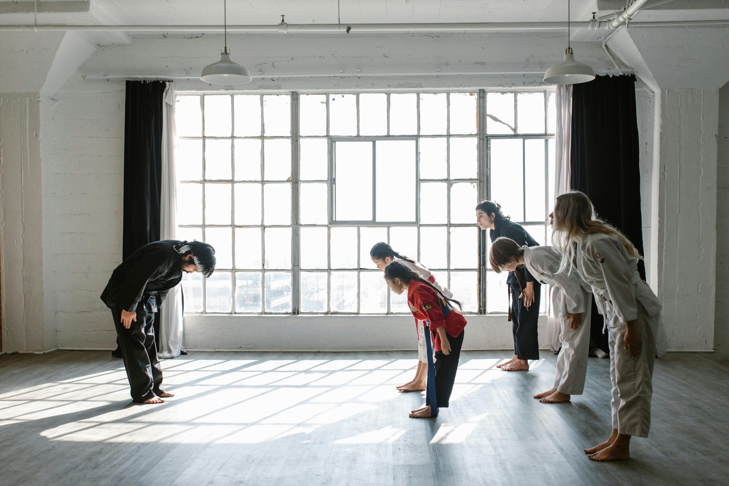 Martial arts students bowing in a sunlit dojo. Perfect for fitness and sports themes.